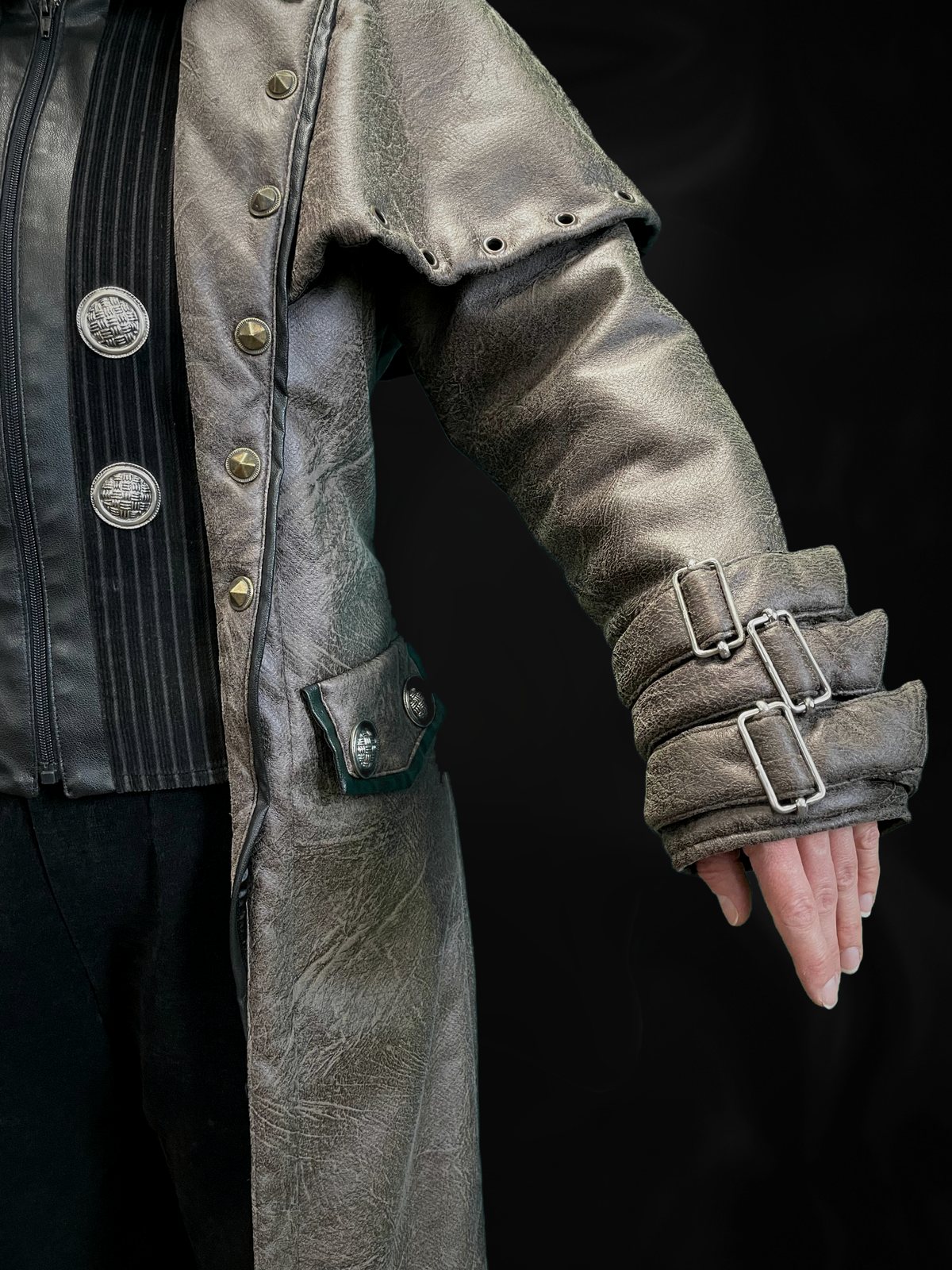 Detail: Ärmel mit drei Schnallen, Taschenklappe mit Zierknöpfen, Nieten am Mantelrand