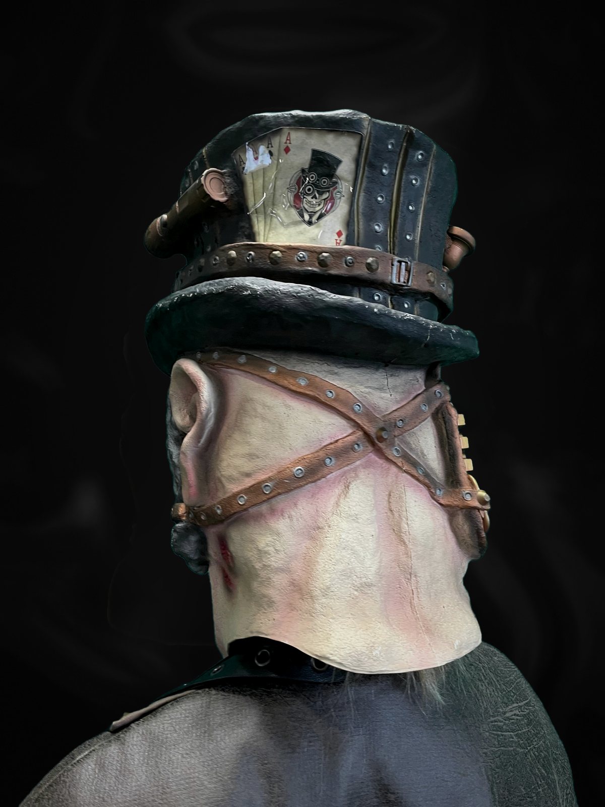 Steampunk-Maske von hinten: gekreuzte Lederriemen mit Nieten, Spielkarten am Zylinder